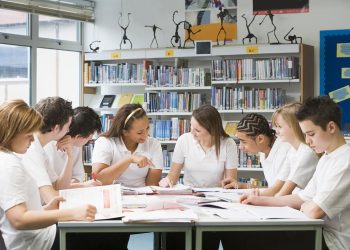 Schoolchildren studying in school library working together on project