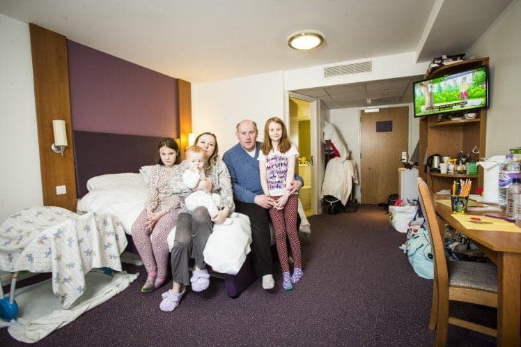 ***EMBARGOED UNTIL 3.00PM GMT*** Luke and Olga Burns, with their children Lolita (brown hair), 11, Alina, 10, and Nicolas, 11 months. The family have been forced to live in hotels for nearly three years after the council failed to find them a house. See SWNS story SWHOTEL; A council has been ordered to rescue a homeless family-of-five after leaving them "trapped" living in a hotel for THREE YEARS - at a staggering cost of £88,000. The Burns moved into a hotel when they were turfed out their flood damaged private rental flat in 2014 and thought they would be there for a week. But two authorities spent months arguing over who should look after them before they were declared "intentionally homeless" - putting an end to any council help. Since April 2014 Luke Burns and his wife Olga - both qualified teachers - have been forced to limp from handout to handout to keep a roof over their heads.