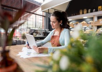 Happy Latin American business woman doing the books at a restaurant