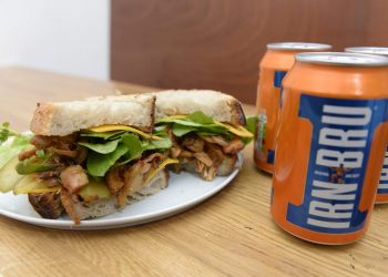 Cafe owner Amelia Sulhunt, from Serenity Now Cafe, Glasgow, Scotland, with a Vegan Irn Bru sandwich made from pulled Jackfruit. The Jackfruit is roasted after Irn Bru is poured on it.   See SWNS story SWSCsandwich; A family-run vegan cafe is set to make taste buds across the city explode with the launch of a new Irn Bru infused winter sandwich. Serenity Now Cafe will soon offer the juicy sandwich served on toasted sourdough bread with BBQ sauce, rocket, cheese and pickles. And the Irn Bru is roasted with pulled jackfruit and mushrooms in the barbecue sauce. The mouthful bite also comes with side-salad, air-fried chips or mac and cheese. Glaswegians have been flocking to try the £6.50 sandwich which will be sold at the cafe based at Great Western Rd, Glasgow.