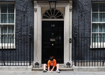 Jess Phillips leaves her son outside No 10 to protest education cuts making school hours shorter (PA)