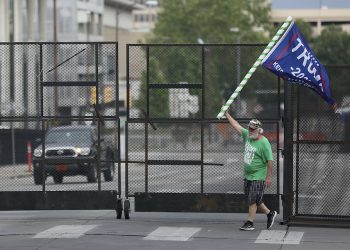 Mike Pellerin waves a Donald Trump campaign flag near a barricade after driving  all night from Austin, Tx. to line up and camp with other Trump supporters on 4th Street and Cheyenne Ave. in downtown Tulsa ahead of Saturday's campaign rally Friday, June 19, 2020. The area for several blocks around the BOK Center is barricaded. Upon arriving Pellerin said he needed to burn some energy before taking a nap. MIKE SIMONS/Tulsa World