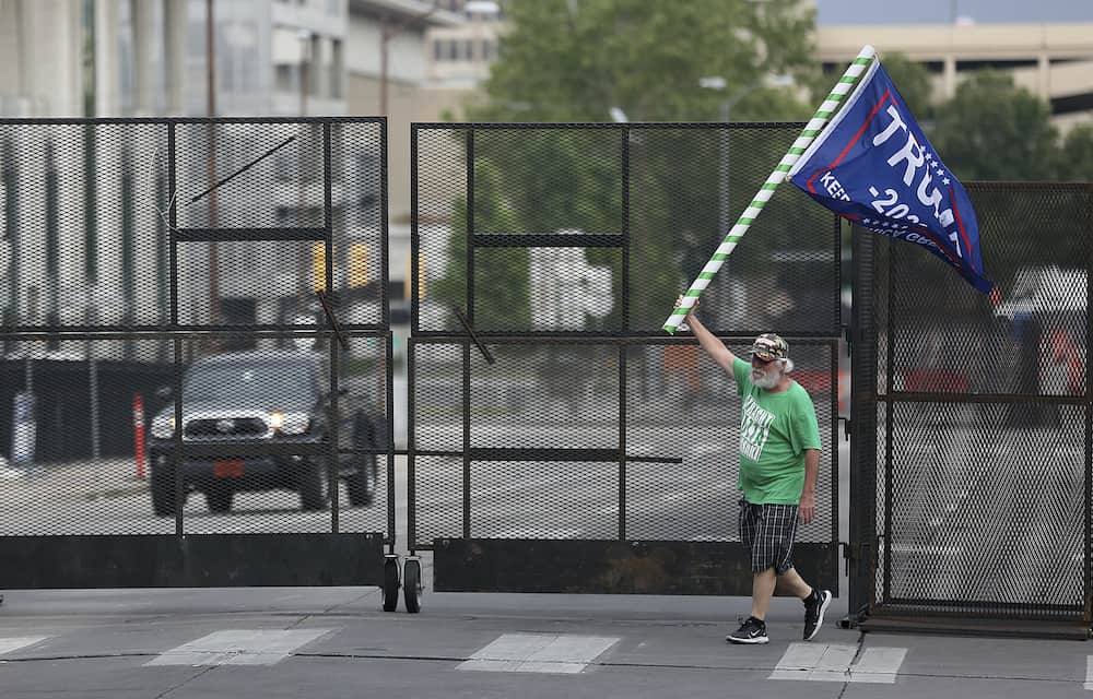 Mike Pellerin waves a Donald Trump campaign flag near a barricade after driving all night from Austin, Tx. to line up and camp with other Trump supporters on 4th Street and Cheyenne Ave. in downtown Tulsa ahead of Saturday's campaign rally Friday, June 19, 2020. The area for several blocks around the BOK Center is barricaded. Upon arriving Pellerin said he needed to burn some energy before taking a nap. MIKE SIMONS/Tulsa World