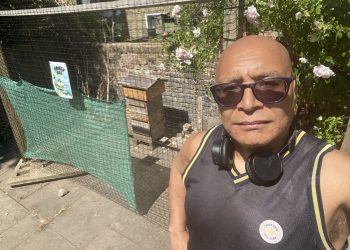 Lee Jasper stands next to the community beehive