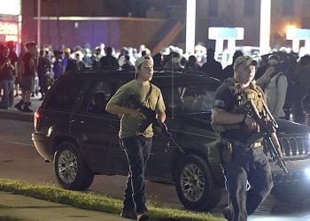 Kyle Rittenhouse, left, with backwards cap, walks along Sheridan Road in Kenosha, Wis., Tuesday, Aug. 25, 2020, with another armed civilian. Prosecutors on Thursday, Aug. 27, 2020 charged Rittenhouse, a 17-year-old from Illinois in the fatal shooting of two protesters and the wounding of a third in Kenosha, Wisconsin, during a night of unrest following the weekend police shooting of Jacob Blake. (Adam Rogan/The Journal Times via AP)