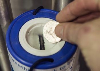 PICTURE POSED BY PHOTOGRAPHER
A coin is dropped into a charity collection container in London.
