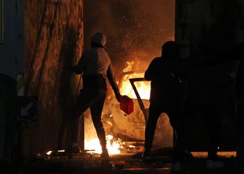 A nationalist throws a petrol canister the Peace Gates in Lanark Way, Belfast during further unrest in Belfast. Picture date: Wednesday April 7, 2021.
