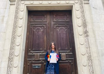 Journalist Andra Maciuca holding her British citizenship certificate and the flags of Romania and the UK.