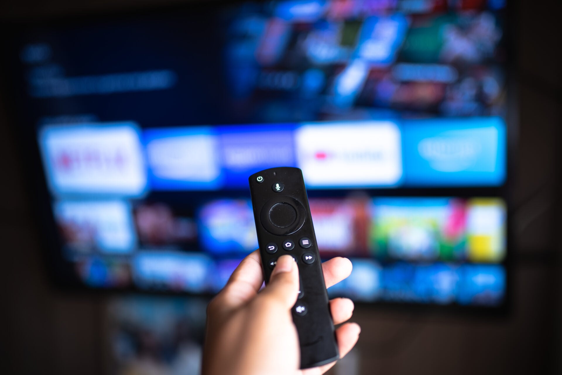 Rio de Janeiro / Brazil- February 3, 2021: amazon fire tv stick remote in hand with selective focus tv background. During the COVID-19 lockout