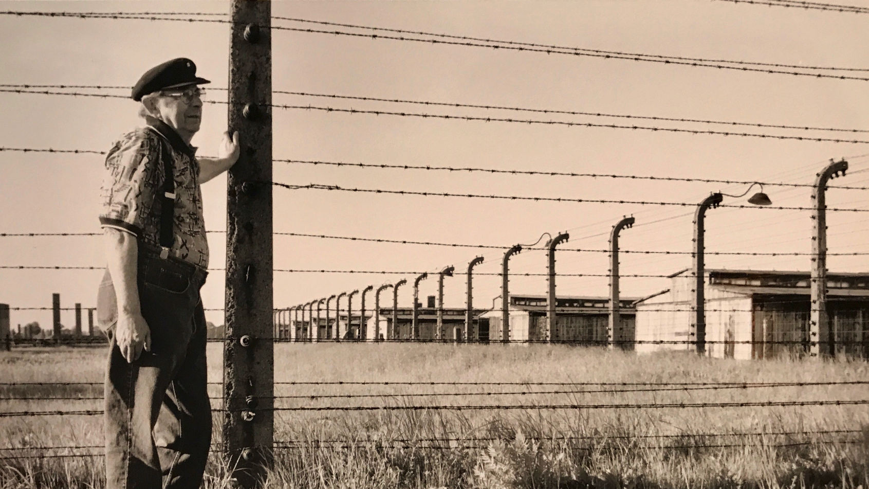 Leopold stands beside the barbed wire at Auschwitz-Birkenau during a return visit decades after his liberation. One of the surviving twins subjected to Josef Mengele’s experiments, he revisited the site to bear witness and to affirm survival in the face of the camp’s attempt at annihilation. Credit: Richard K. Lowy/Pauli Ann Carriere/Belters News
